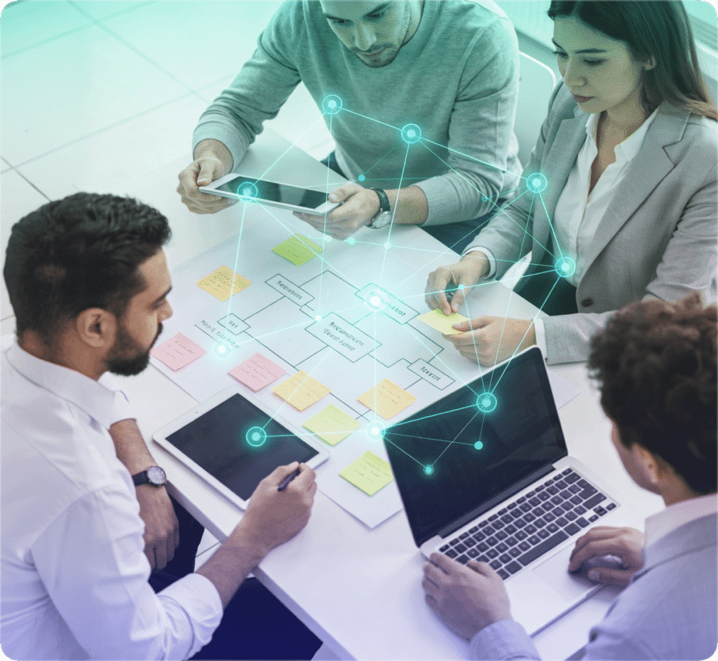 Four people collaborate in a business meeting with laptops, tablets, and sticky notes; a digital overlay represents connections and data flow.